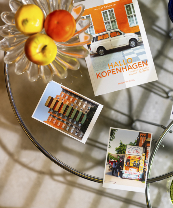 "Hallo Kopenhagen" – Ankerwechsel Verlag Buch im Studio von Ain't No Trash auf Glastisch mit Postkarten und Obstschale