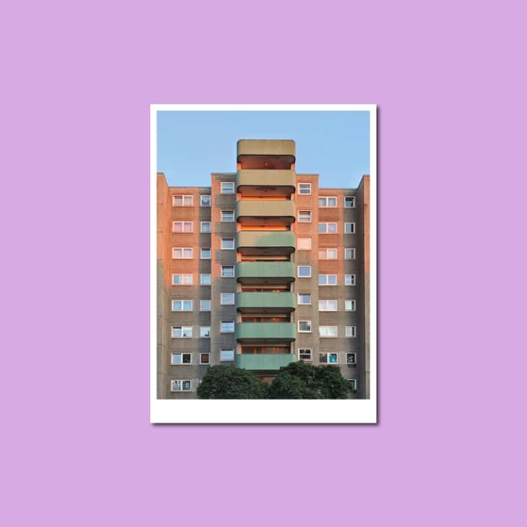 Postkarte mit einem Plattenbau in Berlin-Wedding, orange-grüne Balkone vor blauem Himmel