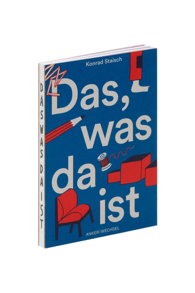 „Das, was da ist“ von Konrad Staisch, stehend fotografiert: blauer Umschlag mit dem Titel in großen hellen Buchstaben, dazwischen rote Illustrationen von Zollstock, Bleistift, Garnrolle und Sessel. Am Rücken steht der Titel senkrecht, die offene Fadenbindung ist sichtbar.
